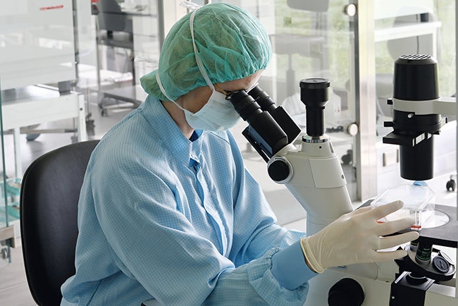 Medical technician looking into microscope